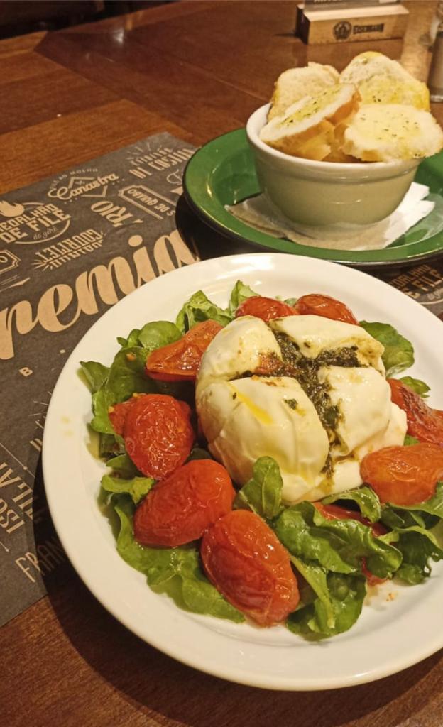 Burrata com tomate cereja, pesto de manjerição e rúcula.